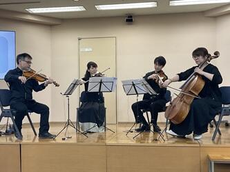 舞台上で演奏を行う演奏者と鑑賞している学生ら