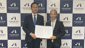 日本空港ビルデング社長と本学学長が並んで協定書を持っている様子