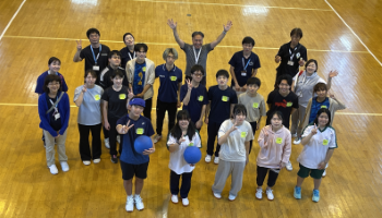 参加者と学生、つくば市職員の方々など20名程度が体育館アリーナに立ち、上を見上げる形での集合写真