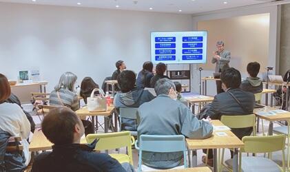 会場内の様子。正面にスライド投影のモニターがあり、モニターの右側に大杉教授が立って講演している。